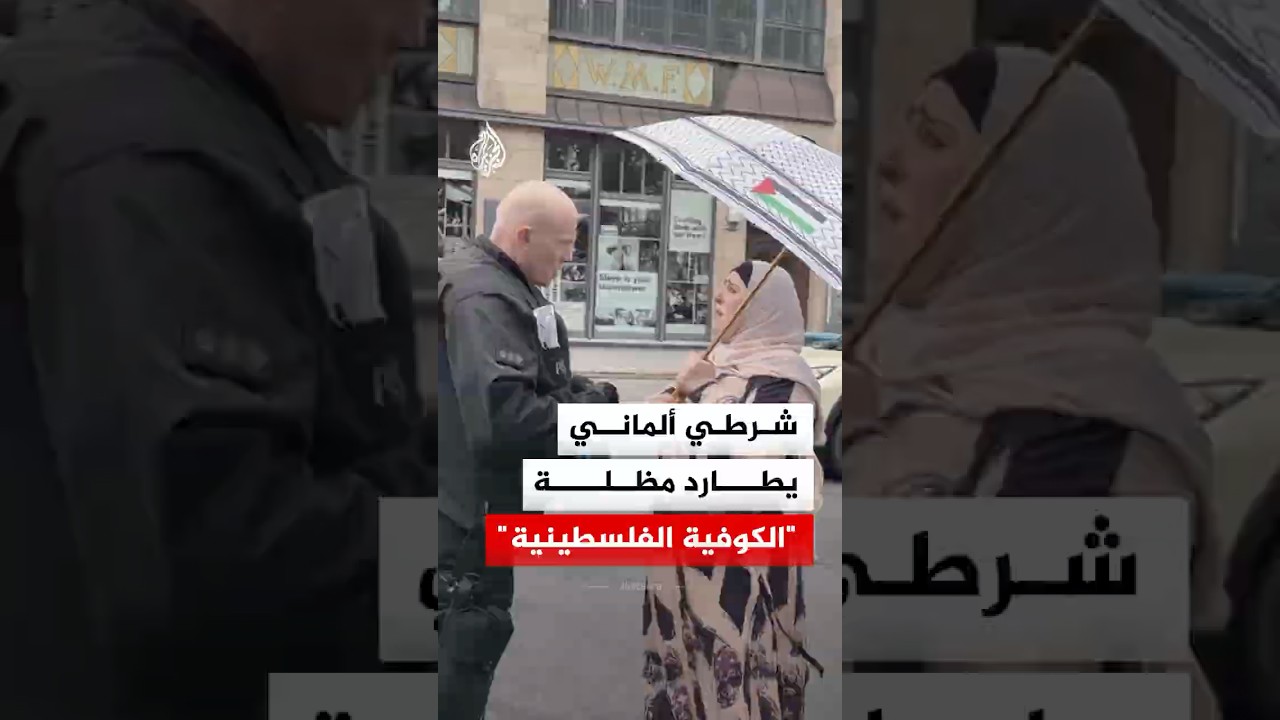 شرطي ألماني يحاول منع سيدة من استخدام مظلة مصممة بشكل "الكوفية الفلسطينية"